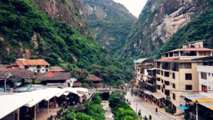 The town of Aguas Calientes (Machu Picchu Pueblo) nestled in a deep river valley at the base of lush, steep green mountains – Qosqo Expeditions