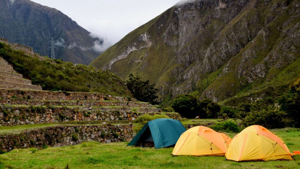 Camping tents set up on a grassy field next to ancient Inca terraces on the classic Inca Trail to Machu Picchu – Qosqo Expeditions