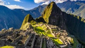 A stunning panoramic view of the ancient Inca citadel of Machu Picchu, with its intricate stone ruins and green terraces set against the Andes mountains. – Qosqo Expeditions