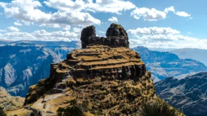 The ancient fortress of Waqrapukara, known for its horn-shaped peak and Inca terraces, perched high above a deep Andean canyon in Peru. – Qosqo Expeditions