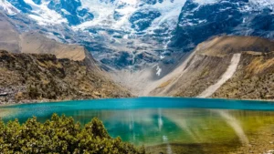 The tranquil, turquoise waters of Humantay Lake in Cusco, with the massive, snow-covered Humantay glacier rising directly from its shore. – Qosqo Expeditions