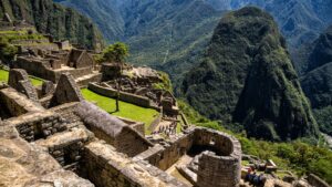 A view from the upper sector of the Machu Picchu citadel, looking down on the main plaza, stone buildings, and surrounding green mountains – Qosqo Expeditions