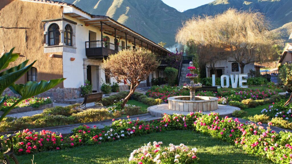 The beautiful garden courtyard of a luxury hotel in Cusco or the Sacred Valley, featuring a central fountain and colorful flowerbeds, characteristic of the best luxury hotels in Cusco – Qosqo Expeditions