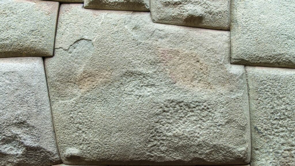 A detailed close-up of the famous Twelve-Angled Stone, showing its perfect, mortarless fit with the surrounding polygonal stones of the Inca wall on Hatun Rumiyoc street in Cusco, Peru – Qosqo Expeditions