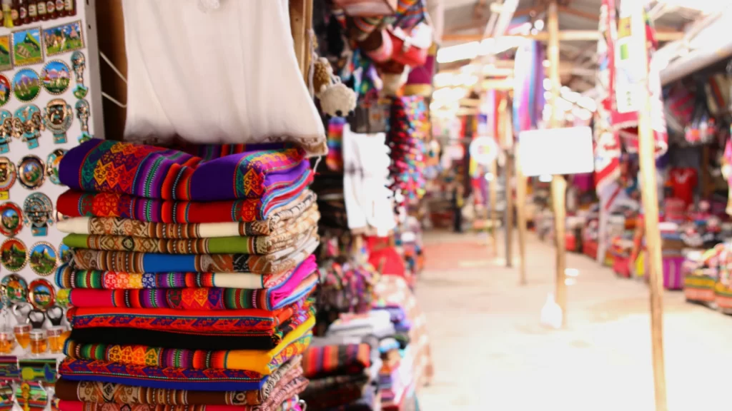Traditional market stall in Cusco with colorful folded textiles handmade garments and decorative crafts