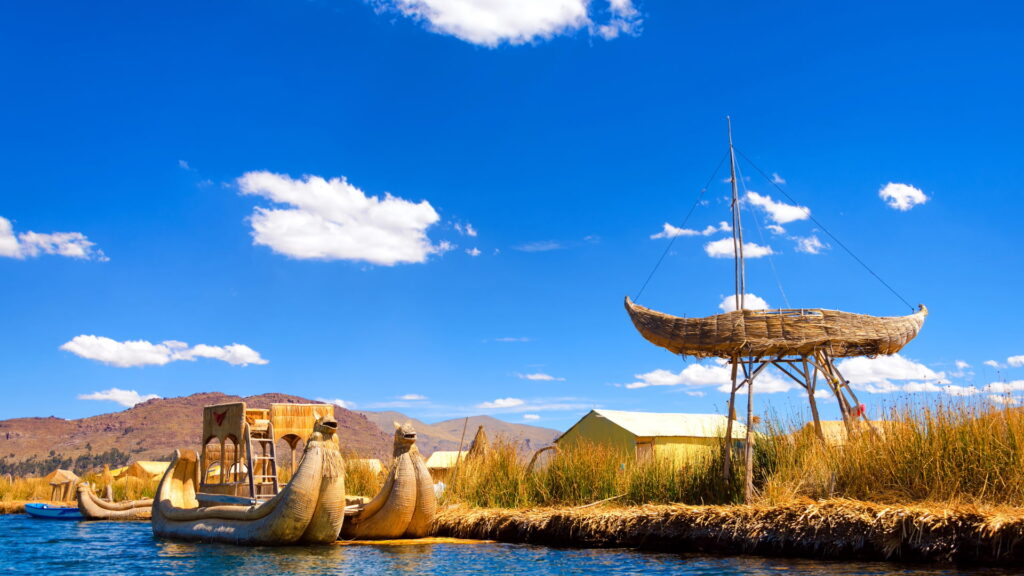 Traditional totora reed boats and floating structures on Lake Titicaca in Puno, Peru, under a bright blue sky-Qosqo Expeditions