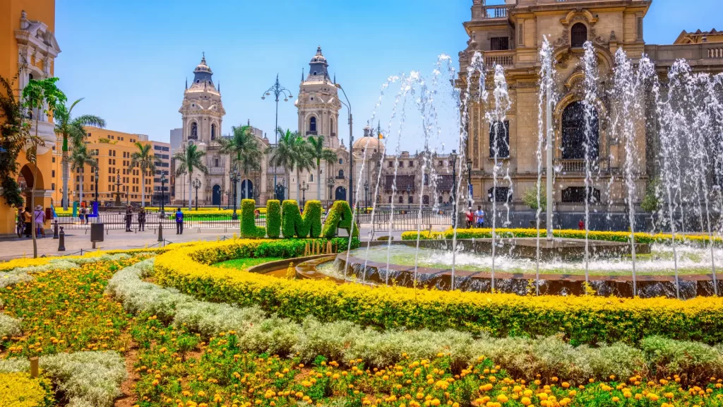 Plaza Mayor in Lima with colonial architecture, cathedral, fountain, and topiary spelling “LIMA”-Qosqo Expeditions