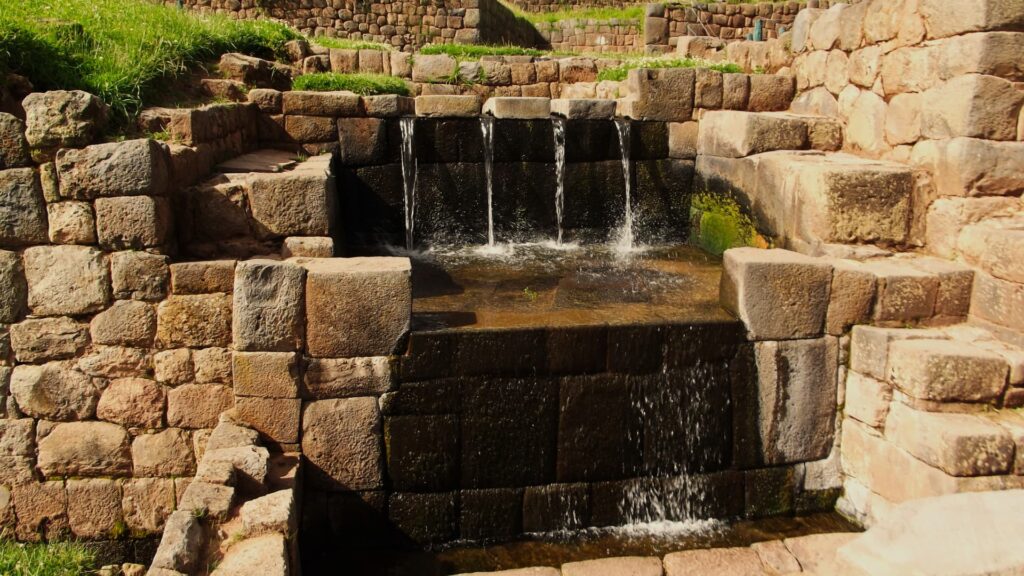Ancient Inca water fountain with cascading flow and stone basins—an example of hydraulic design in Peru water temples.-Qosqo Expeditions