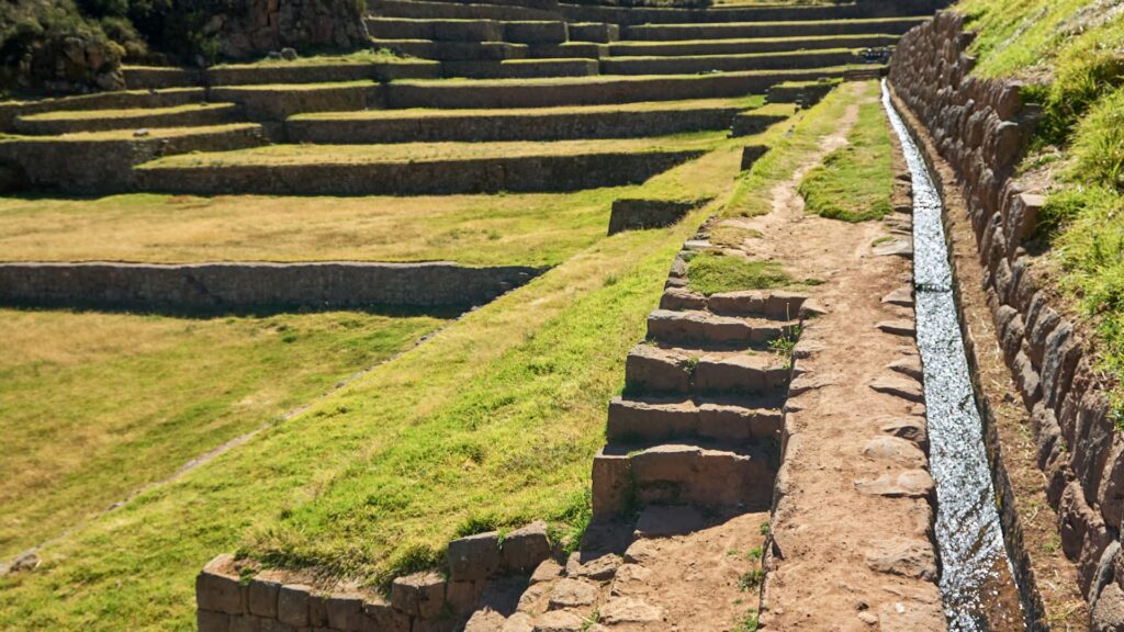 Stone irrigation channel alongside agricultural terraces—an example of hydraulic design found in Peru water temples.-Qosqo Expeditions