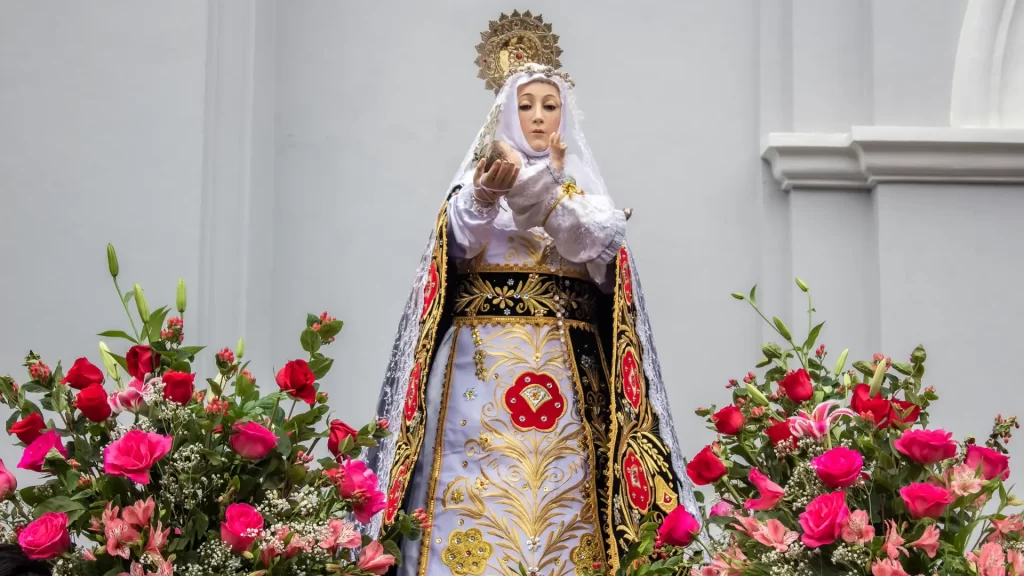 Statue of Santa Rosa de Lima surrounded by pink roses during a procession in Peru-Qosqo Expeditions