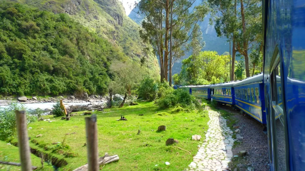 Blue train traveling through green Andean mountains near Cusco, Peru—gateway to popular trekking routes-Qosqo Expeditions