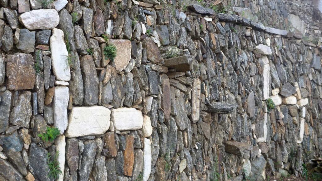 Irregular stone wall with patches of vegetation—architectural detail found along the Choquequirao trek Peru.-Qosqo Expeditions
