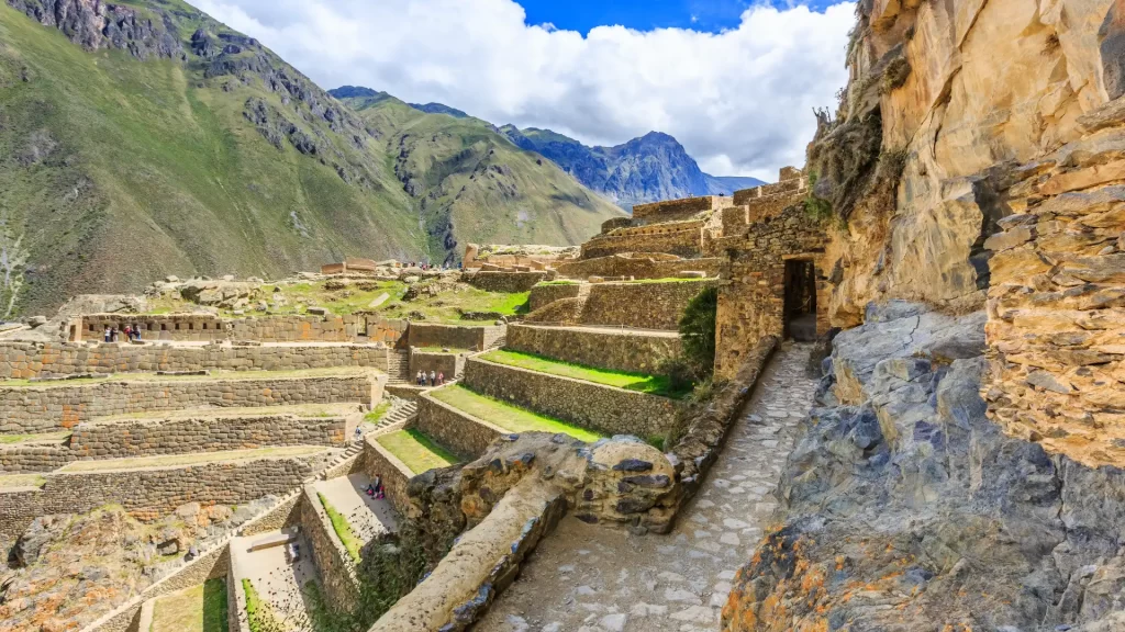 Sunlit Inca terraces and stone structures at Ollantaytambo, framed by steep green mountains—featured in the guide to Ollantaytambo.-Qosqo Expeditions