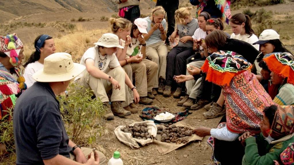 Tourists sample native potatoes alongside an Andean community during an experiential tourism activity in Cusco.