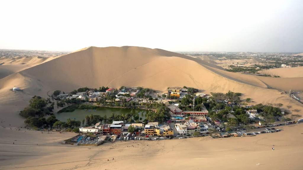 Panoramic aerial view of the Huacachina oasis surrounded by sand dunes in Ica, an ideal destination for tailor made holidays in Peru.