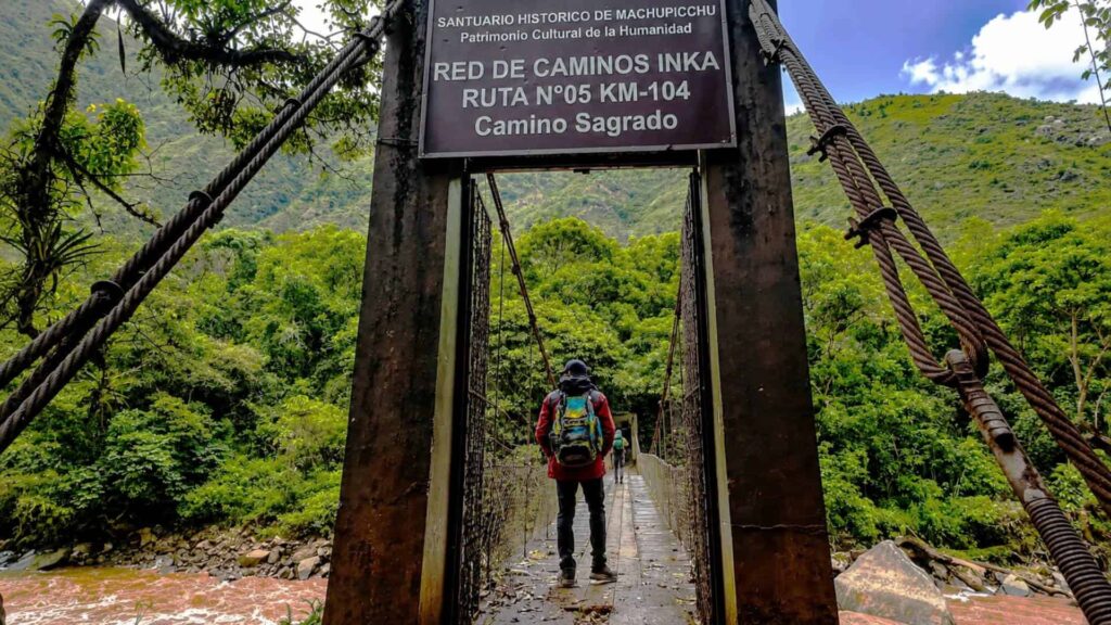 A backpacker crossing the suspension bridge at kilometer 104, the starting point of the 12.3-kilometer Short Inca Trail to Machu Picchu.
