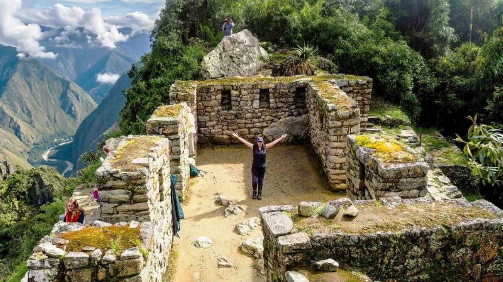 A tourist celebrates with her arms outstretched at Inti Punku, or the Gate of the Sun, at the end of the Inca Trail.