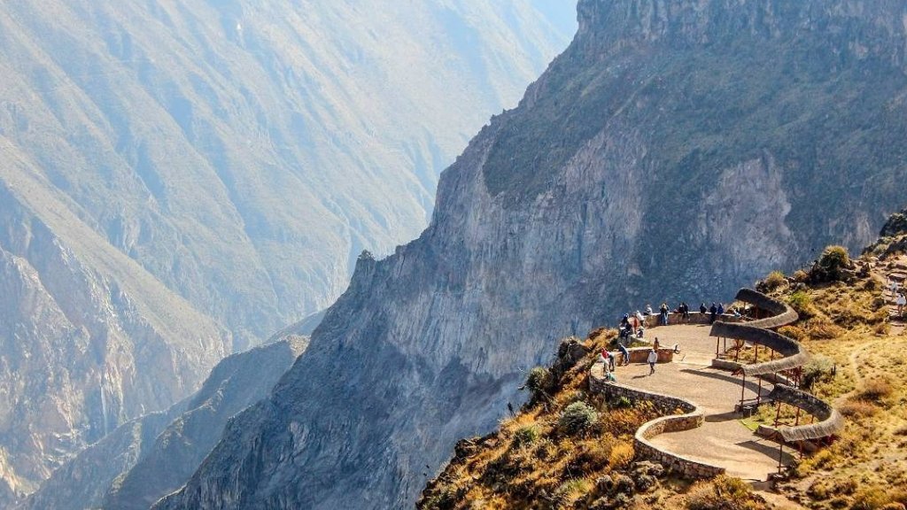 Tourists at the Cruz del Cóndor overlook, gazing out at the Colca Canyon in Arequipa, Peru.