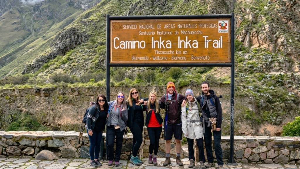 A group of hikers poses in front of the Piscacucho checkpoint at Km 82, an access point to the Inca Trail.