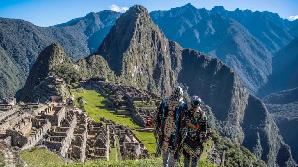 Two hikers in traditional Andean ponchos looking at Machu Picchu after completing the Inca Trail.