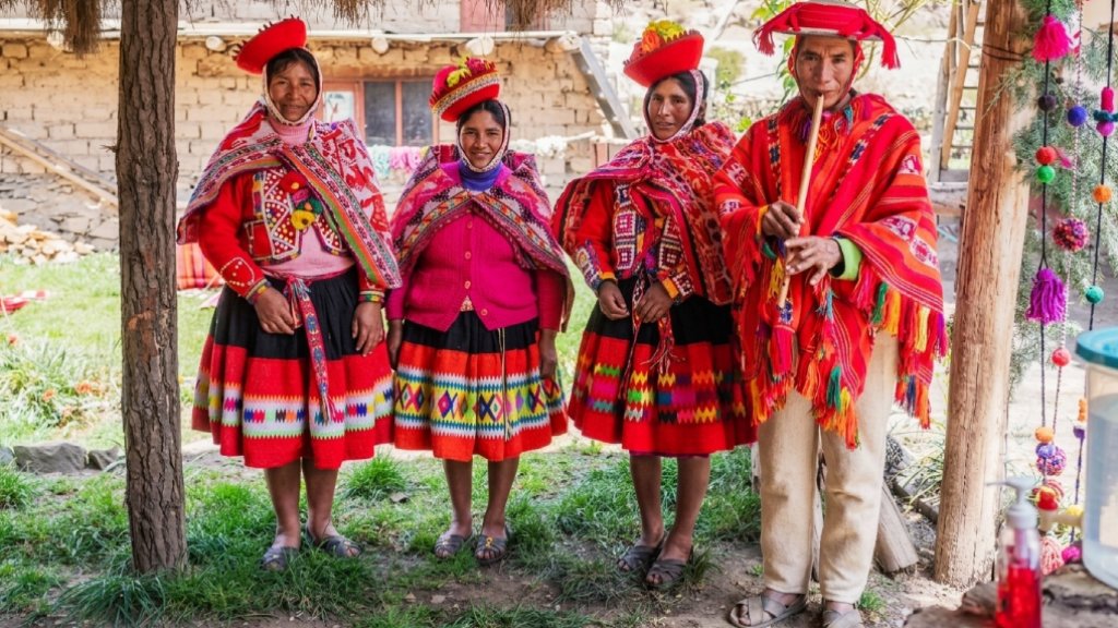 Three women and a man from the Huilloc Community wearing traditional Andean clothing in Cusco.