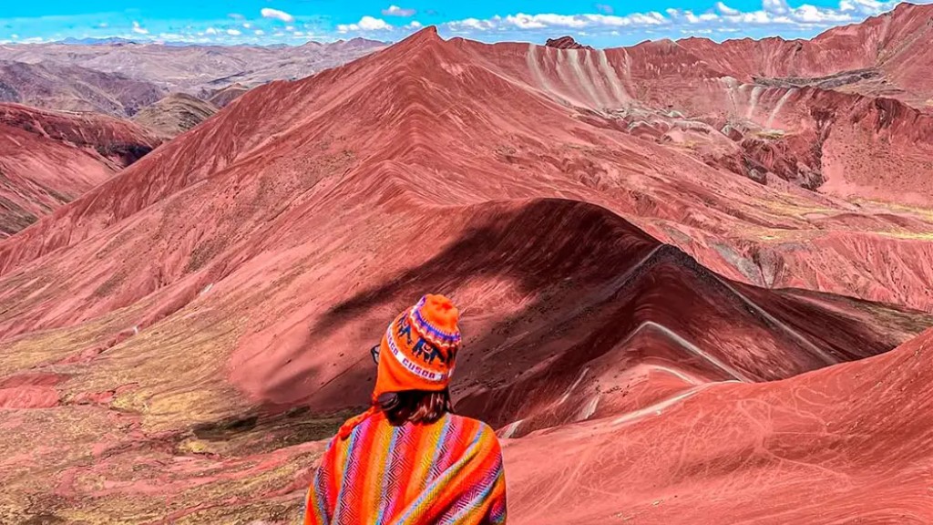 Tourist wearing traditional Andean clothing admiring the reddish mountains of Red Valley Cusco.