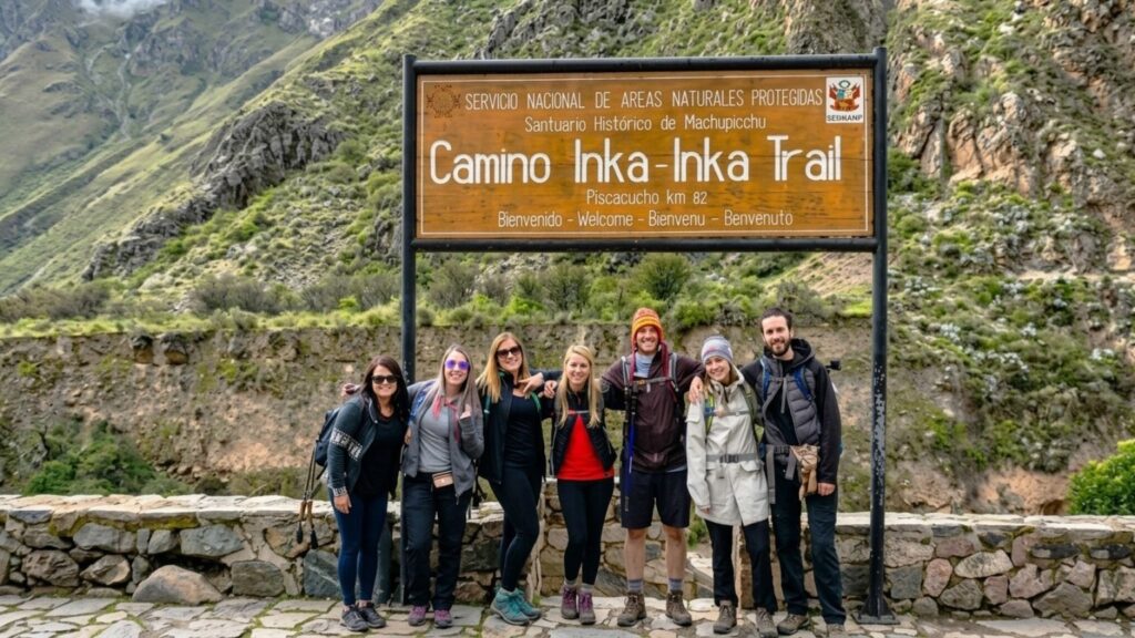 Group of hikers with backpacks standing beside the Inca Trail sign at Km 82.