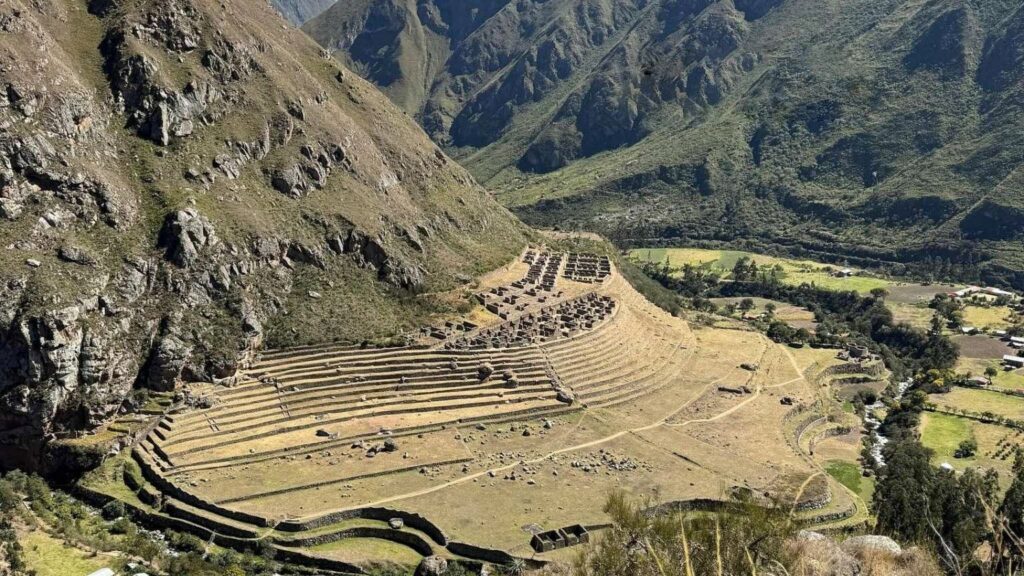 Panoramic view of the Llactapata archaeological site with agricultural terraces on a mountain slope.