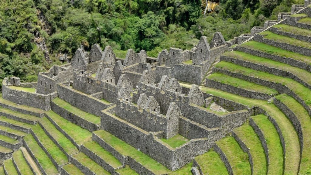 Panoramic view of Wiñay Wayna with agricultural terraces and stone structures on a mountain slope.
