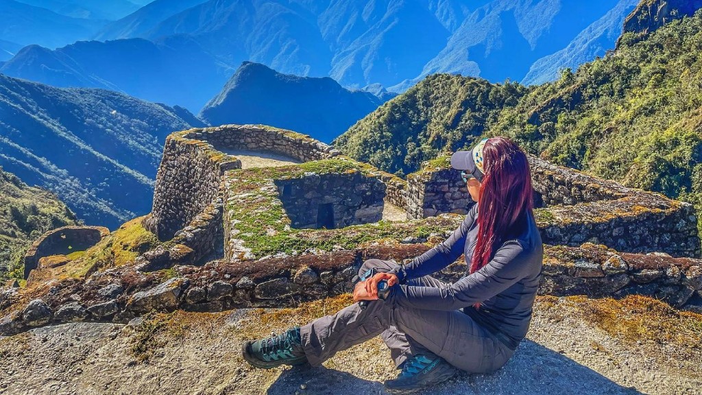 mHiker sitting in front of the stone structures of the Sayacmarca archaeological site on the Inca Trail.