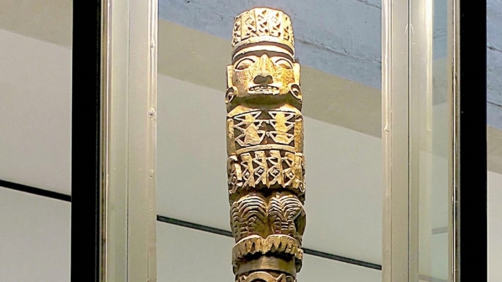 Carved wooden idol of Pachacamac featuring engraved figures and decorative motifs on its surface.